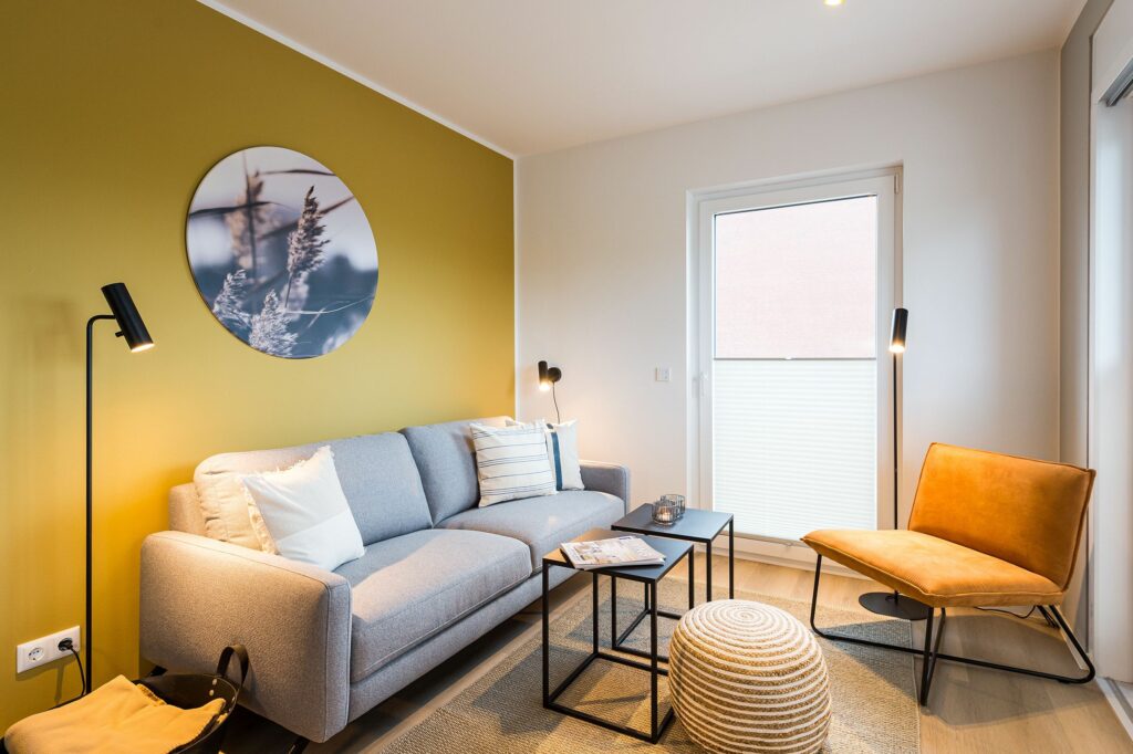Wohnzimmer mit gelber Wand und Sofa in Ferienwohnung Grömitz
