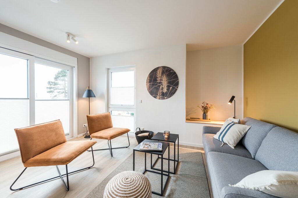 Wohnzimmer mit braunen Hockern und grauem Sofa in Ferienwohnung Grömitz