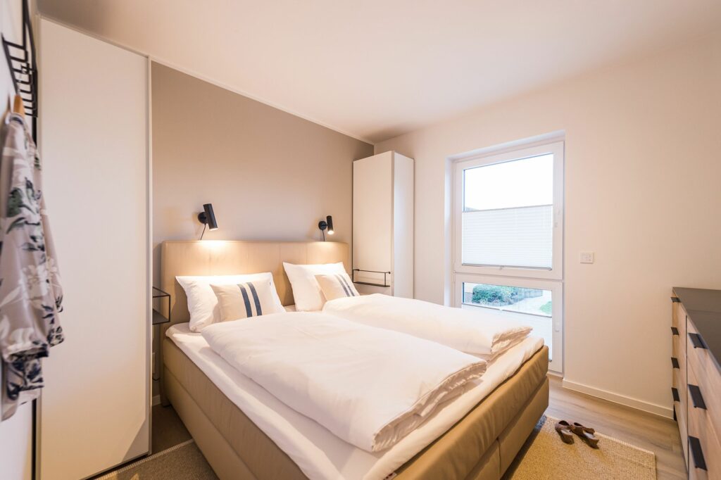 Schlafzimmer mit Doppelbett und Kommode in Ferienwohnung Grömitz
