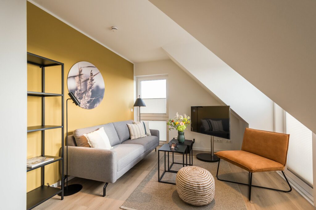 Dachgeschoss Wohnzimmer mit gelber Wand und Sofa in Ferienwohnung Grömitz