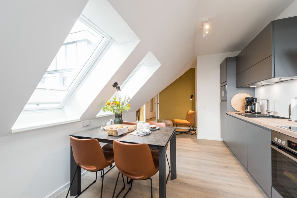 Dachgeschoss Wohnküche mit gedecktem Esstisch für vier Personen in Ferienwohnung Grömitz