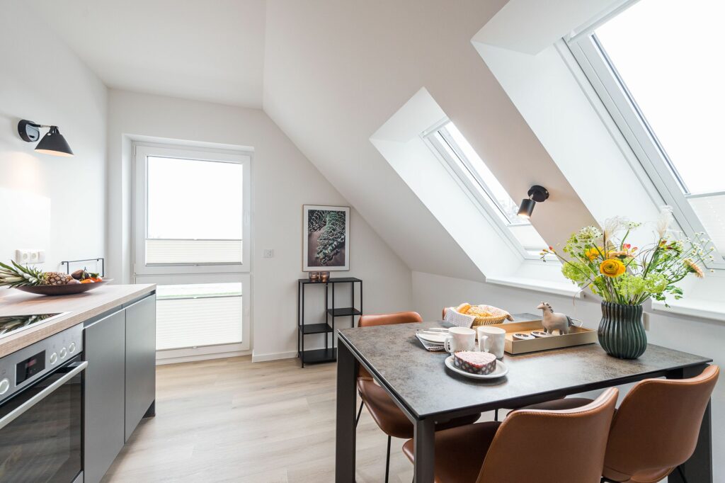 Dachgeschoss Wohnküche mit gedecktem Esstisch für vier Personen in Ferienwohnung Grömitz
