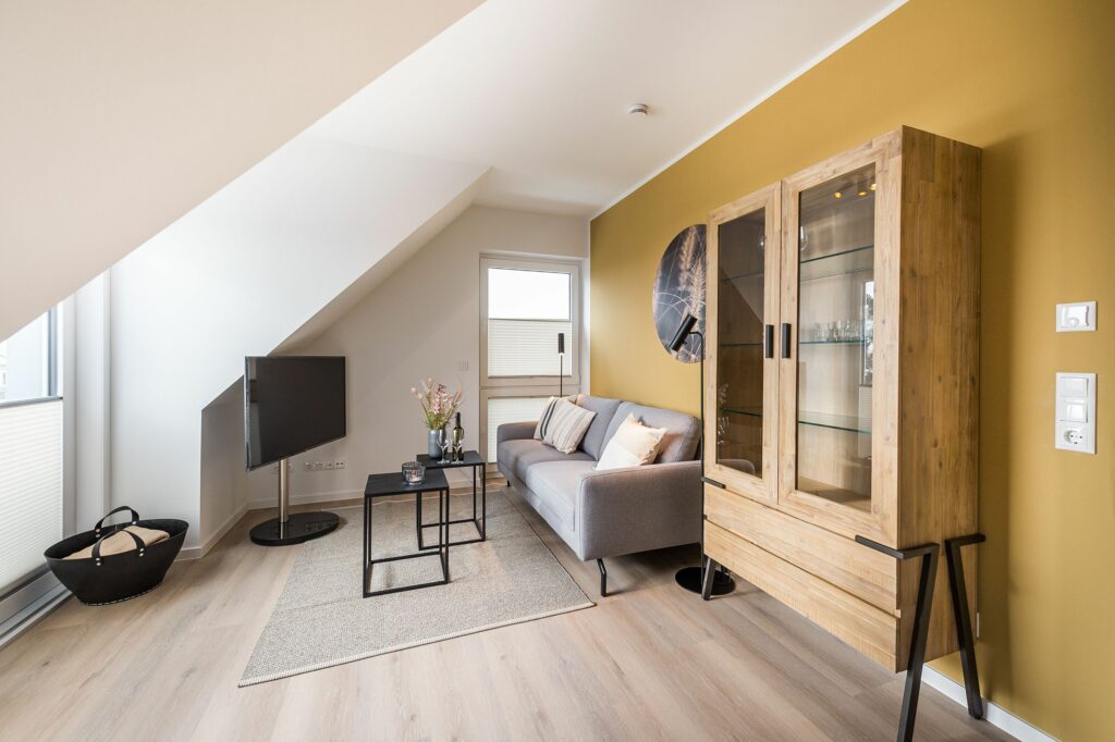 Wohnzimmer mit gelber Wand, Sofa und Fernseher in Ferienwohnung Grömitz