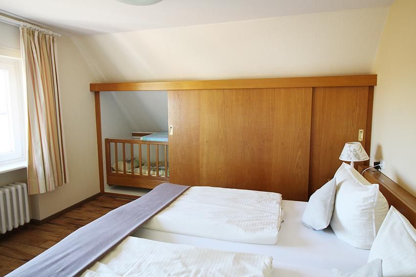Schlafzimmer einer Ferienunterkunft an der Ostsee mit einem Einbauschrank und einem Kinderbett.