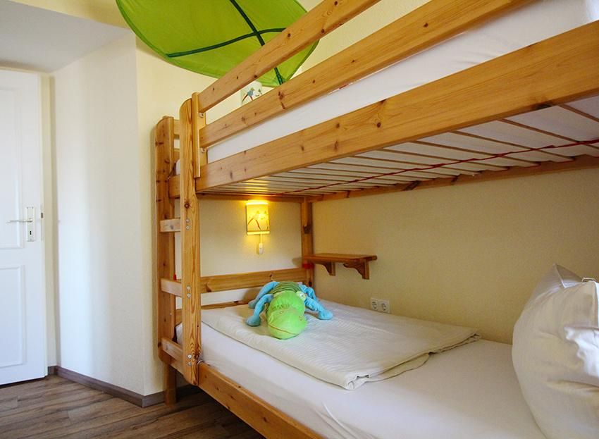 Kinderzimmer in einer Ferienunterkunft an der Ostsee mit einem Hochbett aus Holz.