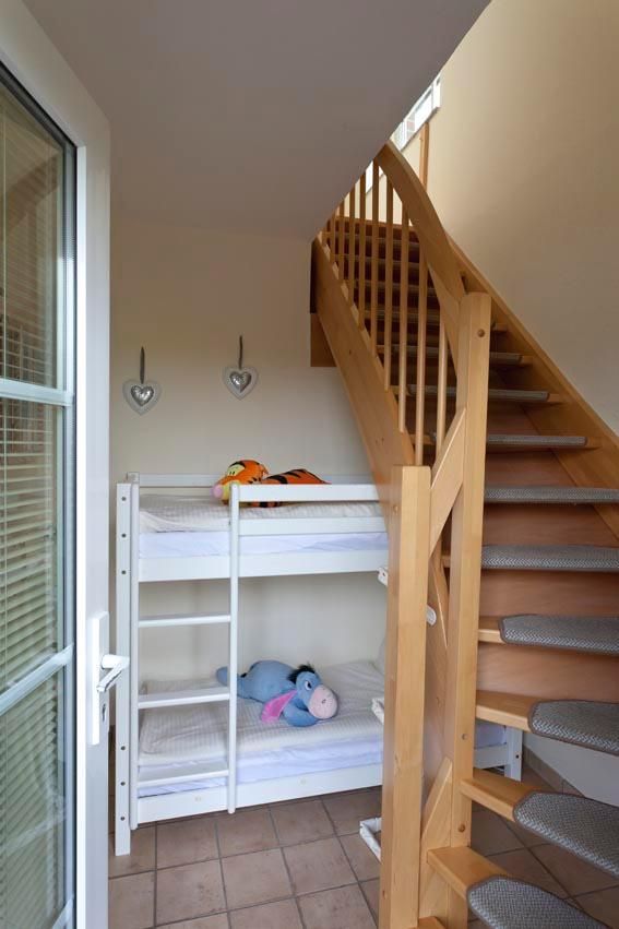 Ein Flur mit einem Doppelbett und einer Holztreppe in einem Ferienhaus an der Ostsee