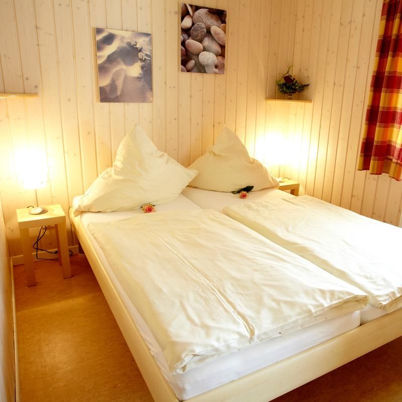 Schlafbereich mit einem Doppelbett und Vertäfelung an den Wänden sorgt für gemütliches Ambiente.