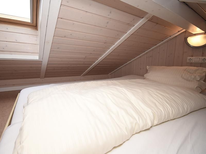 Dachboden Schlafplatz in einem Wellnesshaus an der Ostsee mit Holzbalken und alles in weiß gehalten