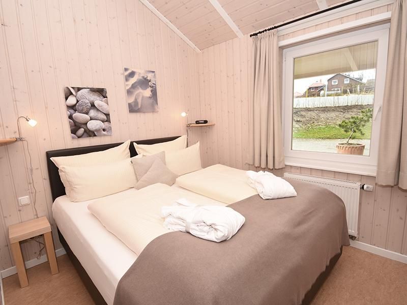 Doppelbett in einem Wellnesshaus an der Ostsee, mit einer wunderschönen Wandvertäfelung. Alles ist in weiß, cremefarbend gehalten.