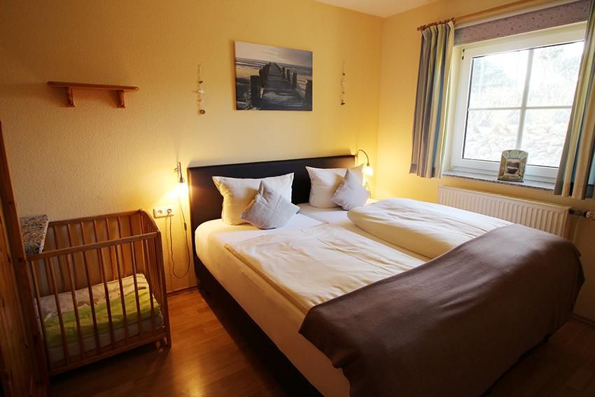 Schlafzimmer mit Doppelbett und Kinderbett in einem Ferienhaus an der Ostsee