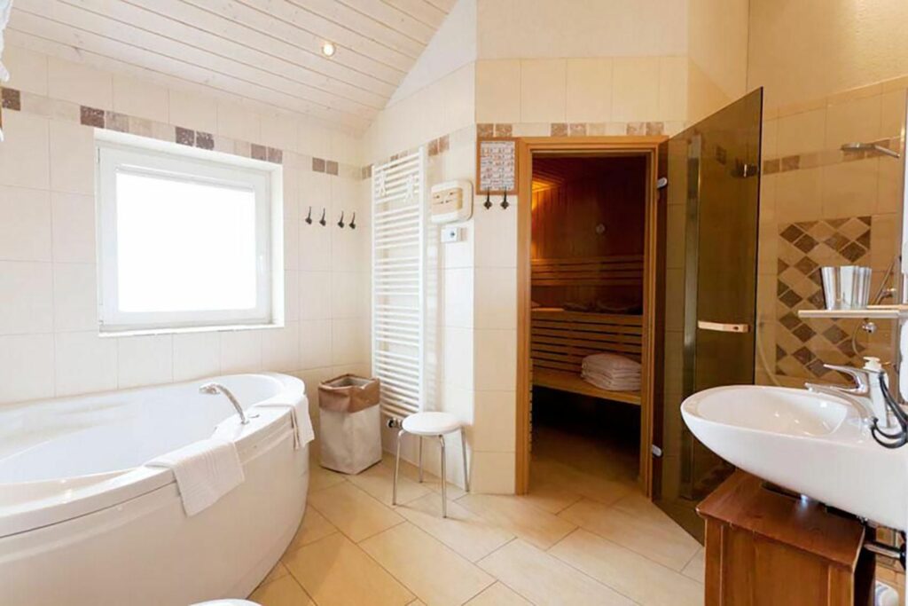 Ein Badezimmer mit einer Whirlwanne und einer privaten Saune im Wellnesshaus in Bliesdorf an der Ostsee.