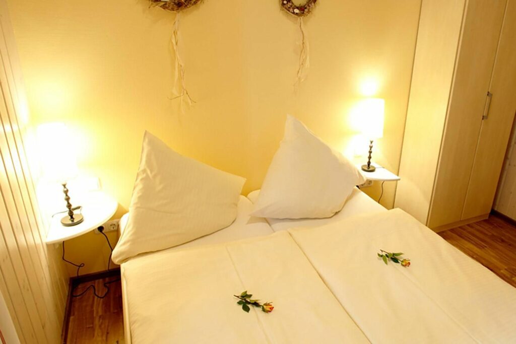 Ein Schlafbereich mit einem doppelbett und zwei Nachtische und Nachttischlampen. im Wellneshaus an der Ostsee