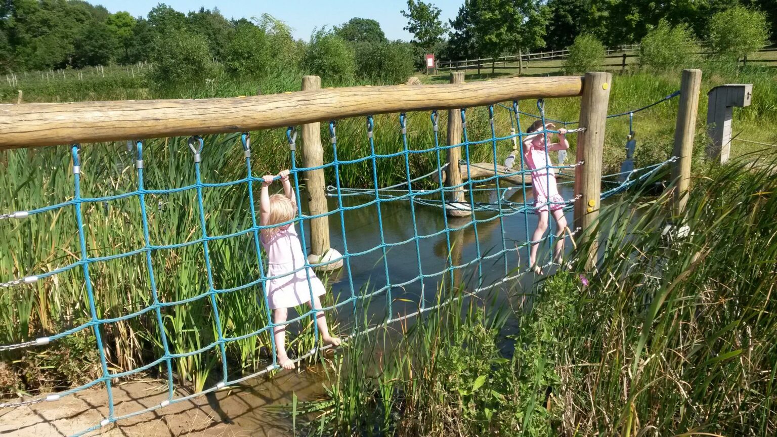 zwei kleine Kinder spielen an einem Klettergerüst am Wasser.