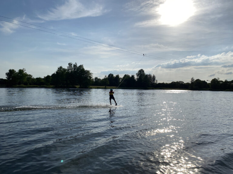 Ein Kind das an einem Seil das Surfen lernt.