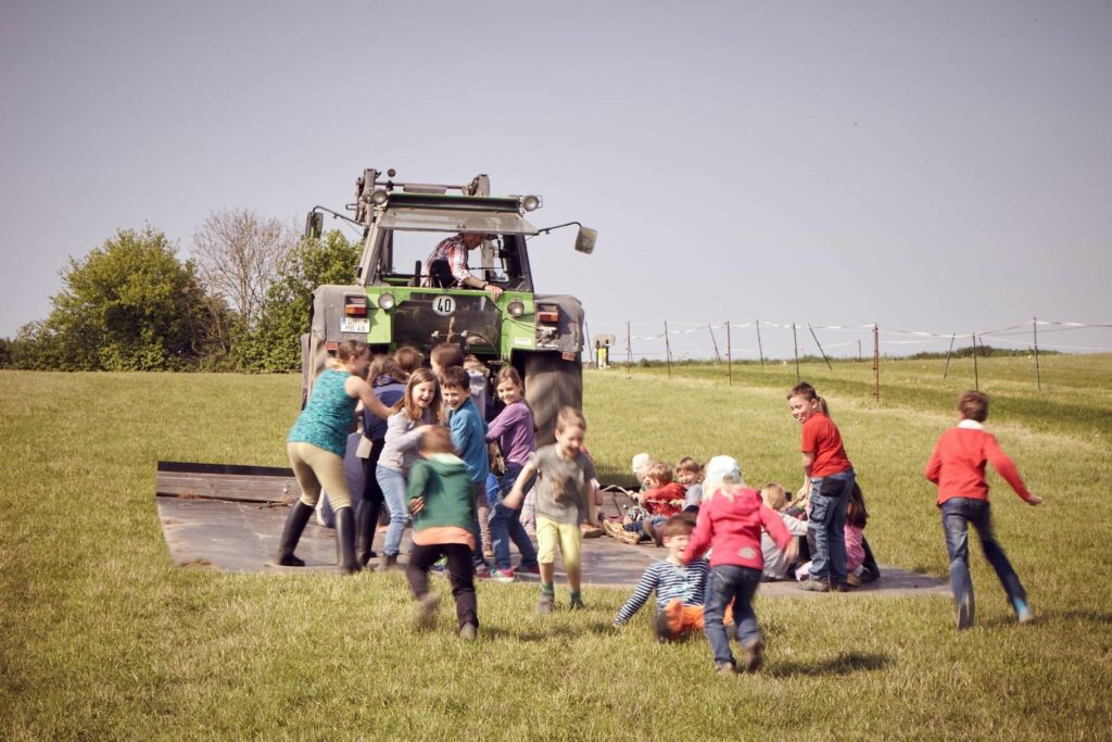 Ein Traktor zieht viele Kinder auf einer Matte hinter sich her