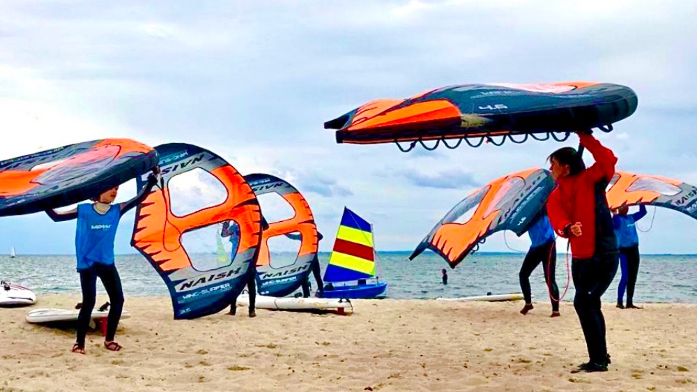 Surfen die Ihr Equipment am Strand tragen.