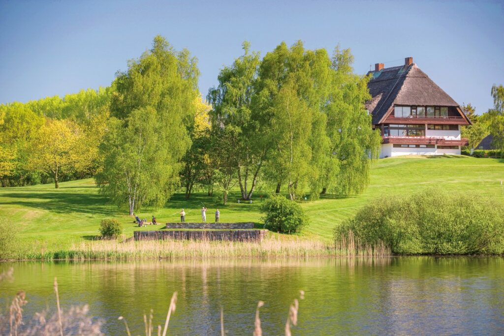 Drei Golfer mit ihrem Equipment auf dem Golfplatz bei schönem Wetter im Sommer