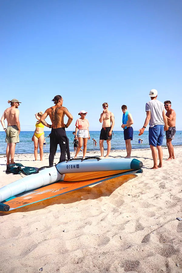 Die Surfschule mit ihren Schüler:innen am Strand