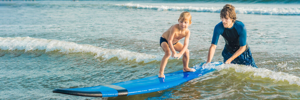 Surfen lernen an der Ostsee. Kind steht auf dem Surfbrett