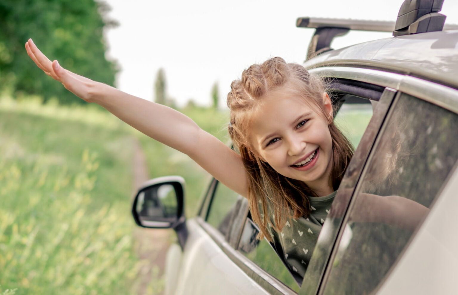 Mädchen im Auto freut sich und streckt die Hand aus