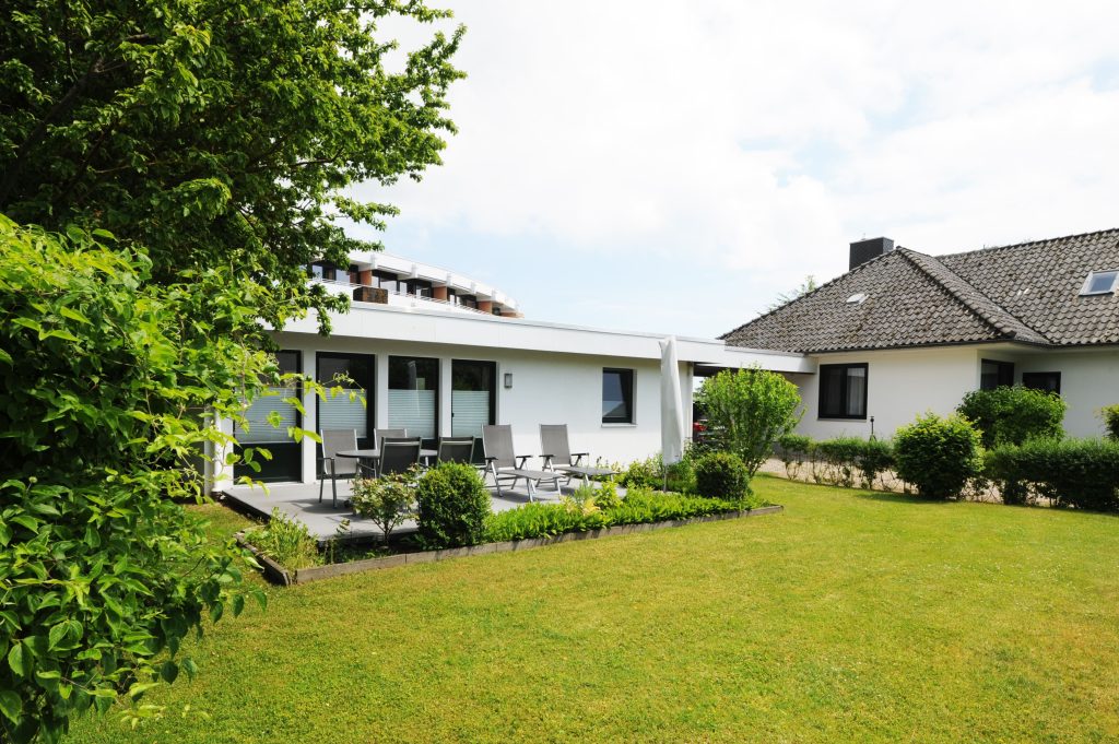Ferienhaus Grömitz mit Terrasse mit Sonnenliegen und grünem Rasen
