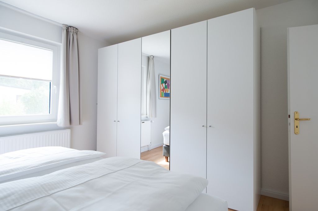 Schlafzimmer mit weißem Spiegelschrank und Doppelbett in Ferienwohnung Grömitz